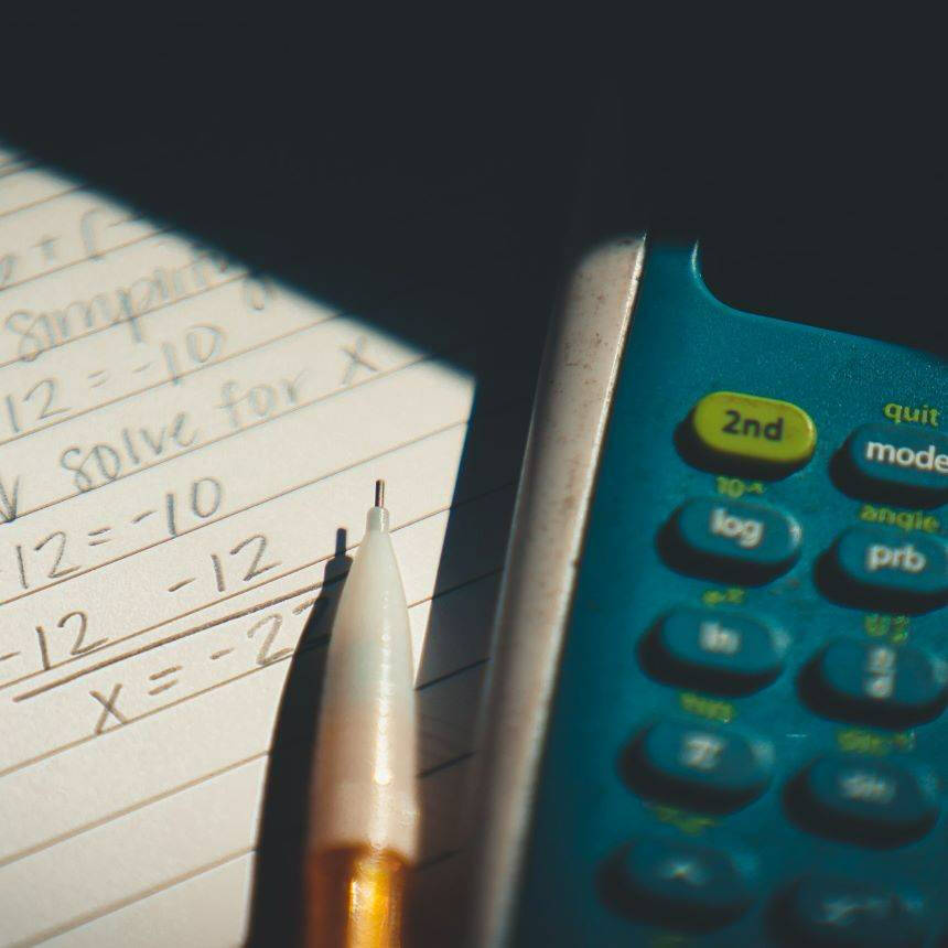 A calculator and pencil resting on top of a notepad.